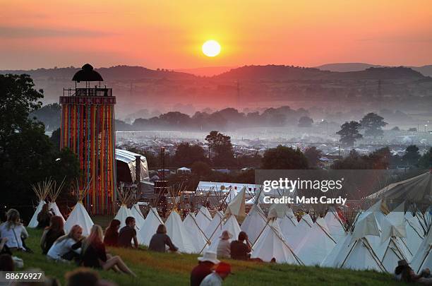 People gather to watch the sunset on a hill above the tipi field as music fans start to arrive at the Glastonbury Festival site at Worthy Farm,...