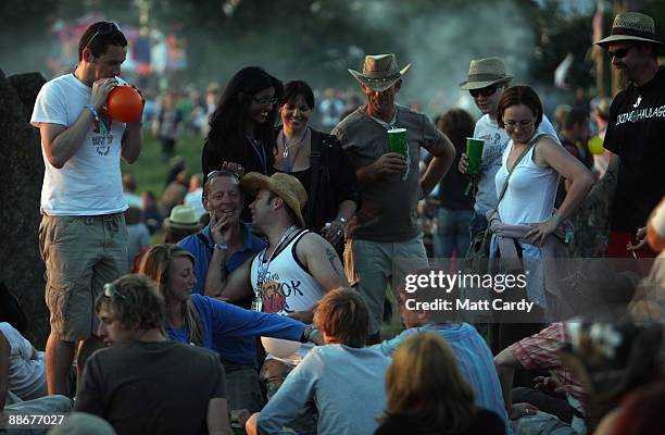People gather to watch the sunset at the stone circle as music fans start to arrive at the Glastonbury Festival site at Worthy Farm, Pilton on June...