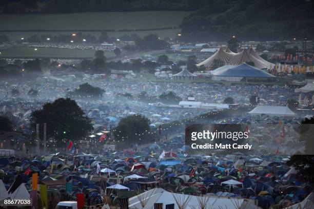 Mist rises over tents as the sun sets as music fans start to arrive at the Glastonbury Festival site at Worthy Farm, Pilton on June 24, 2009 in...