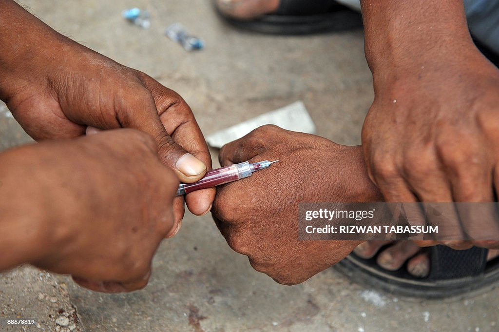A Pakistani drug addict injects another