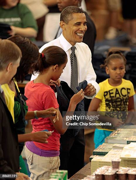 President Barack Obama , first lady Michelle Obama and their daughters Malia and Sasha help volunteers and members of Congress stuff backpacks with...