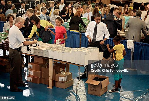 President Barack Obama , first lady Michelle Obama and their daughters Malia and Sasha help volunteers and members of Congress stuff backpacks with...