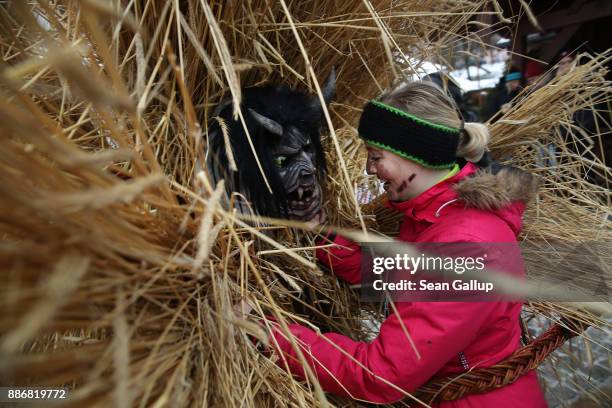 Man dressed in straw and a wooden mask in the form of a figure known locally as "Buttnmandl", or "Shaking Man", embraces a female onlooker with a...