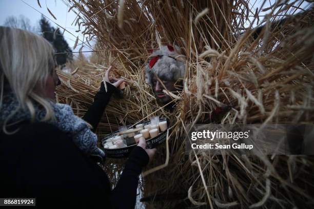 Man dressed in straw and a wooden mask in the form of a figure known locally as "Buttnmandl", or "Shaking Man", receives refreshment duiring a break...