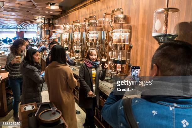 Lady poses for a picture with her coffee at the Starbucks Reserve Roastery store in Shanghai on December 6, 2017. Starbucks opened its largest cafe...
