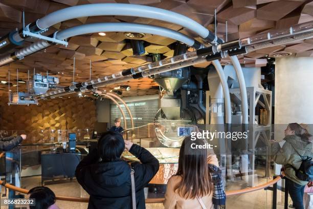 Visitors take pictures at the Starbucks Reserve Roastery store in Shanghai on December 6, 2017. Starbucks opened its largest cafe in the world in...