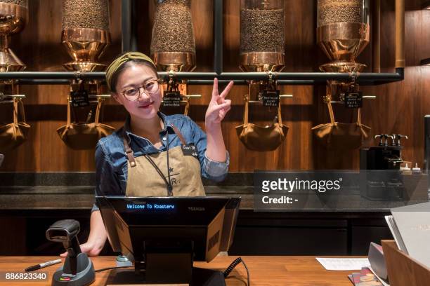 Waitress poses at the Starbucks Reserve Roastery store in Shanghai on December 6, 2017. Starbucks opened its largest cafe in the world in Shanghai on...
