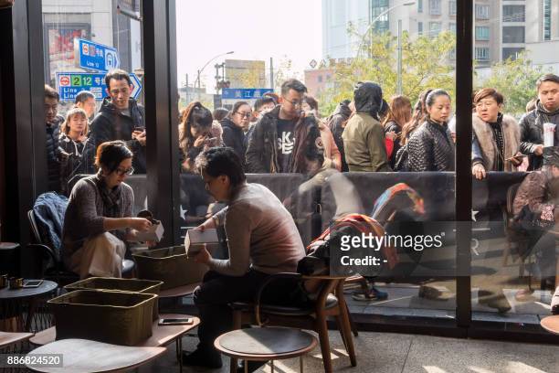 Visitors wait to enter the Starbucks Reserve Roastery outlet in Shanghai on December 6, 2017. Starbucks opened its largest cafe in the world in...