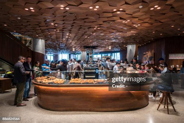 Visitors wait for their coffee at the Starbucks Reserve Roastery outlet in Shanghai on December 6, 2017. Starbucks opened its largest cafe in the...