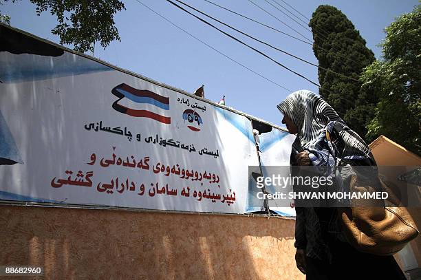 An Iraqi woman walks past an election campaign banner plastered to a wall in the northern city of Sulaimaniyah, 330 kms from Baghdad, on June 25,...