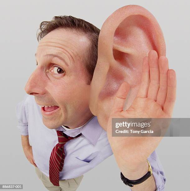 man cupping hand over big ear (digital composite) - human ear foto e immagini stock