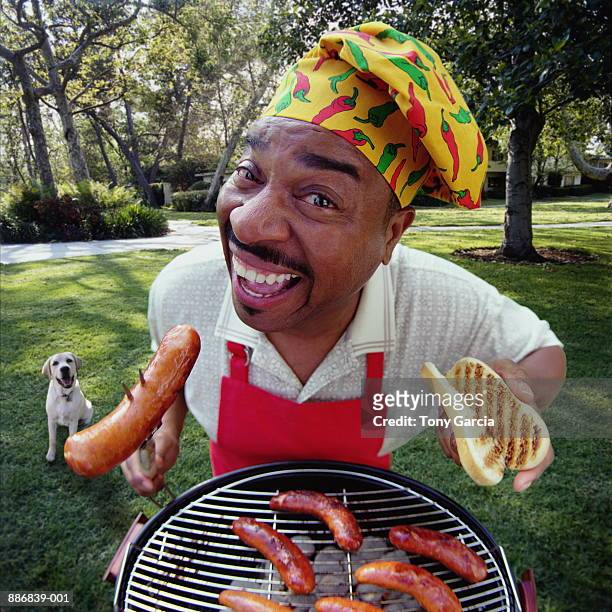 man barbecuing hotdogs on lawn, dog in background (digital composite) - moustaches animales fotografías e imágenes de stock