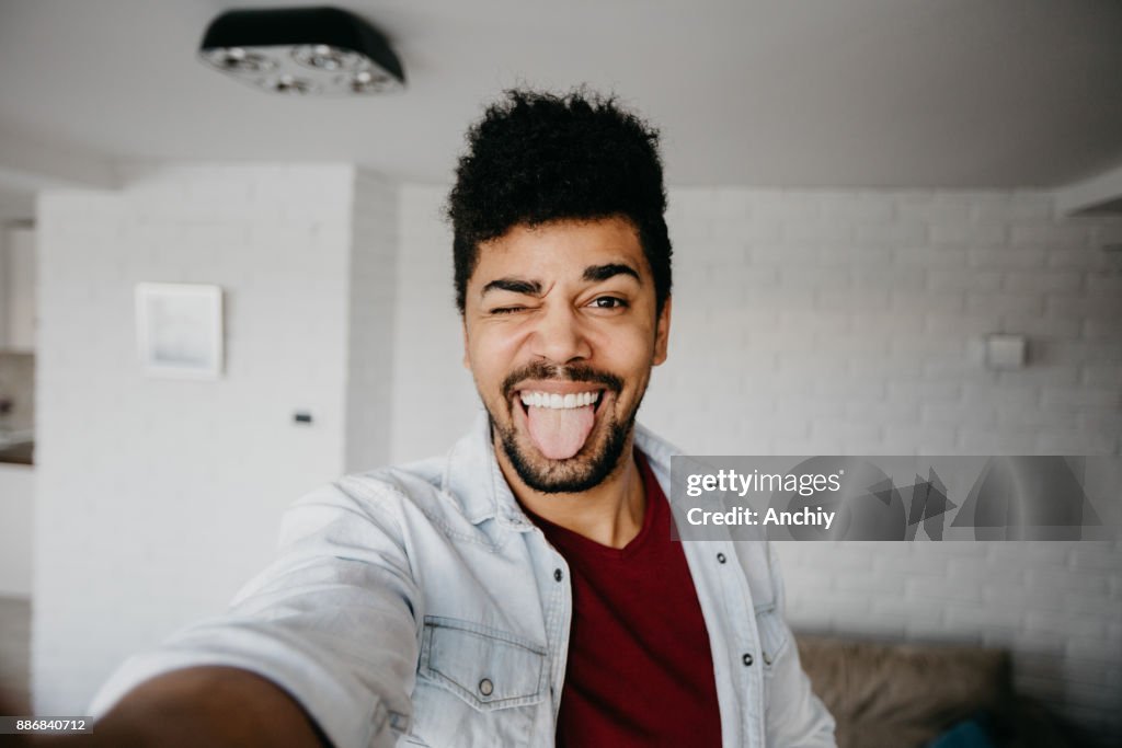 Man winking to a camera and taking a selfie