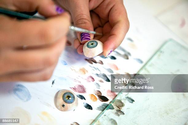 a woman painting blue prosthetic eyes - occhio di vetro foto e immagini stock