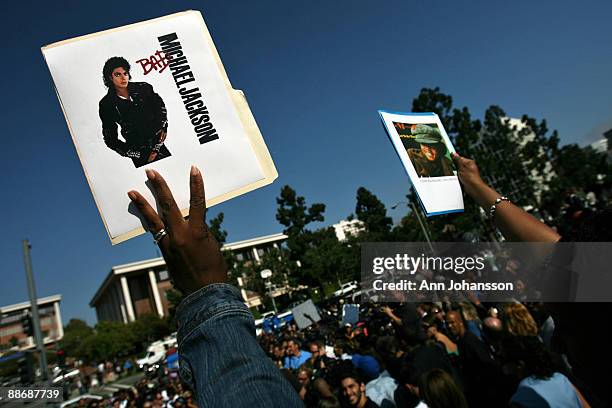 People hold up Michael Jackson pictures as media and spectators wait for a news conference about Michael Jackson's death at UCLA Medical Plaza June...