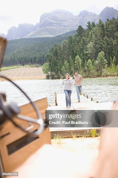 couple running along pier at lake - following car stock pictures, royalty-free photos & images
