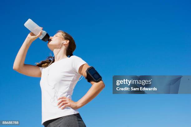 woman runner drinking from water bottle - young woman standing against clear sky stock pictures, royalty-free photos & images