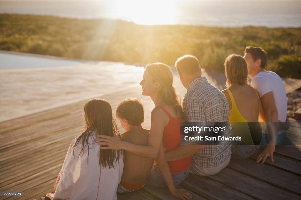 Family sitting on deck by swimming pool