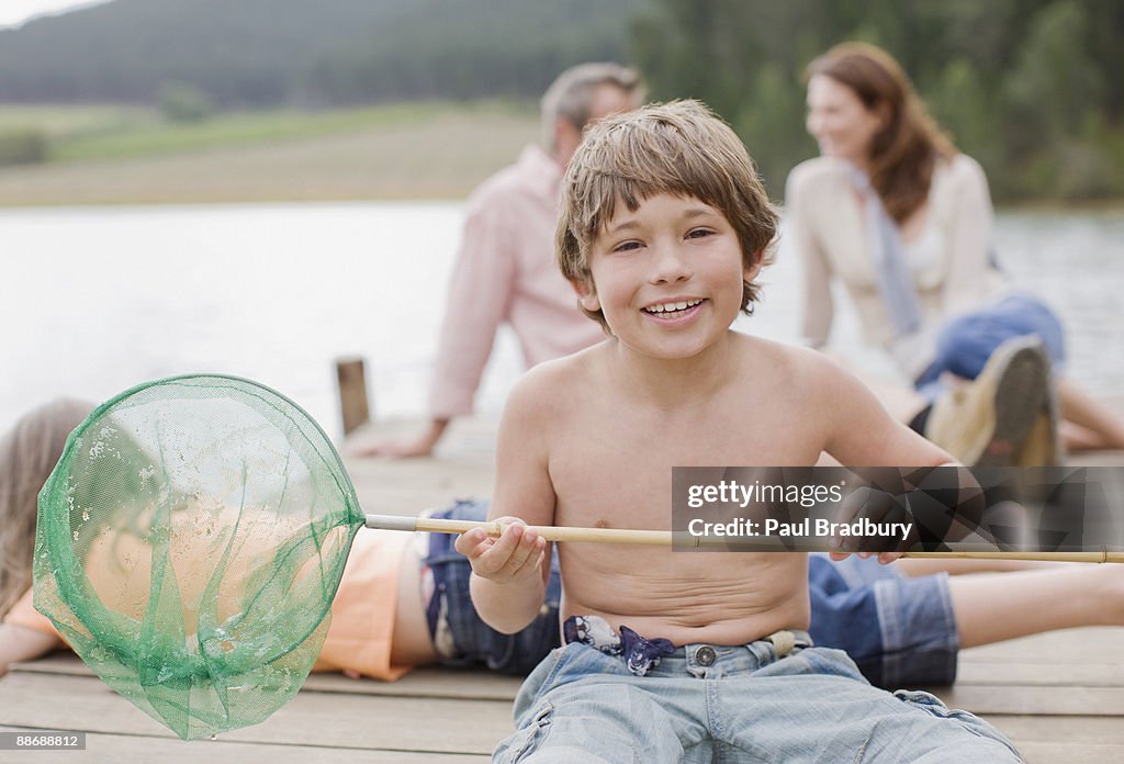 Boy with net and family on pier by lake