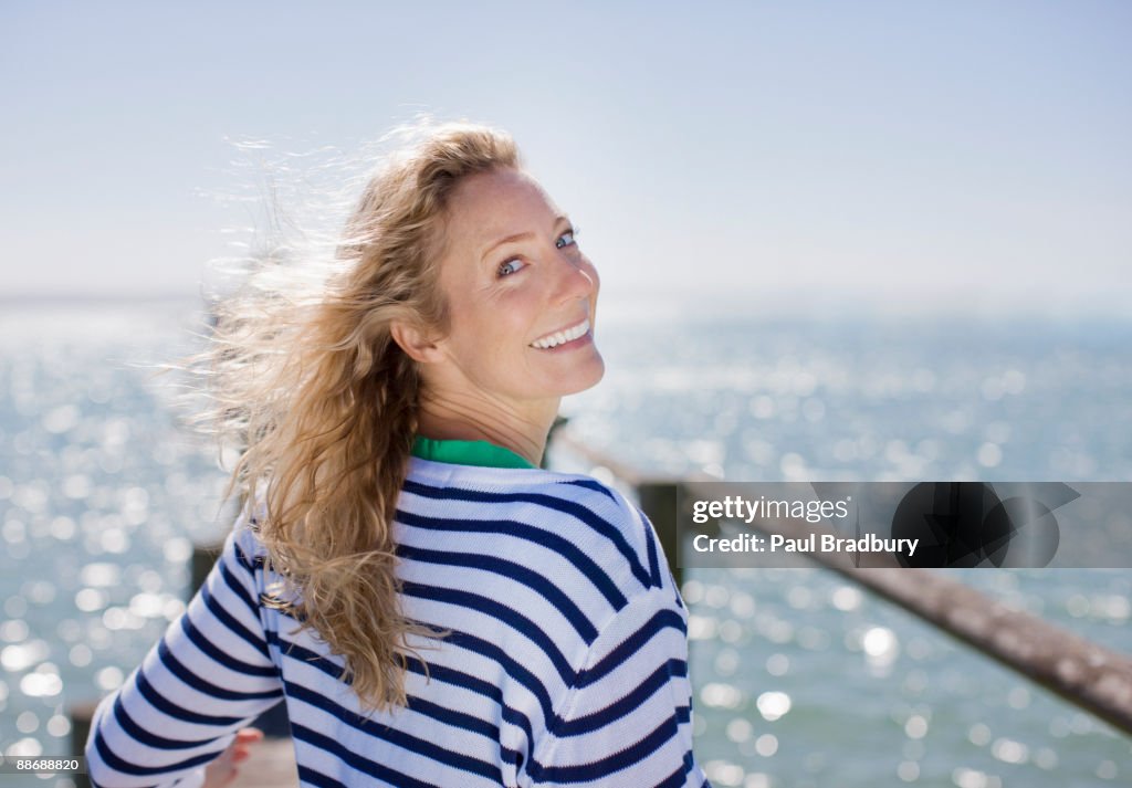 Woman smiling on pier by ocean