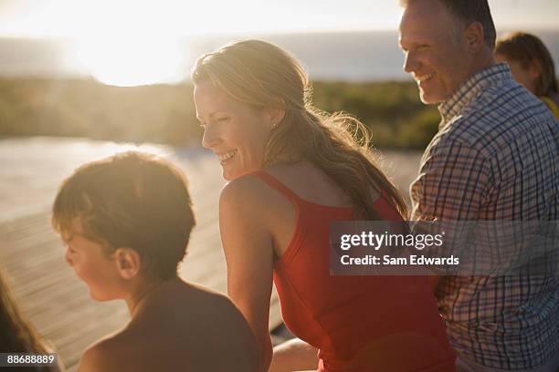familie sitzen an deck in der nachmittagssonne - sun flare couple stock-fotos und bilder