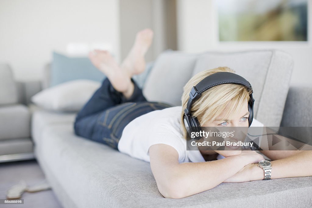 Mulher ouvindo fones de ouvido na sala de estar