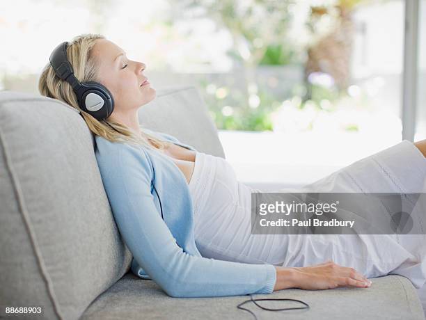 woman listening to headphones in living room - music room stockfoto's en -beelden