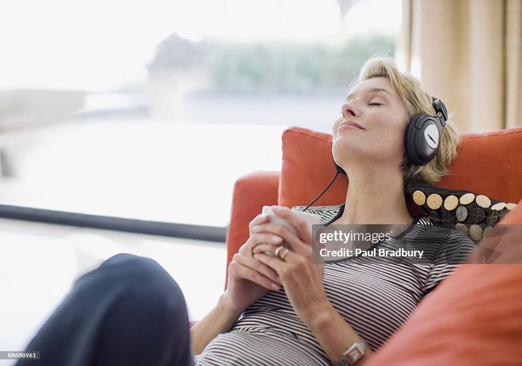 Woman listening to headphones on sofa