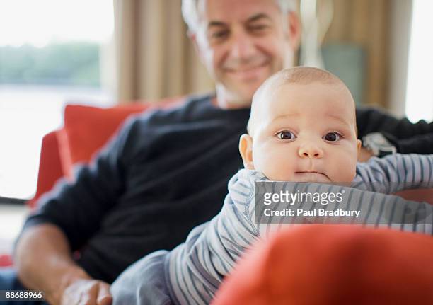 homem brincando com o bebê no sofá - baby grandpa imagens e fotografias de stock