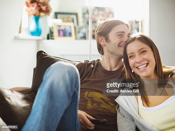 couple sitting on sofa - mid adult men stock pictures, royalty-free photos & images