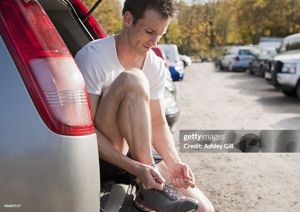 Man tying shoes in hatchback of car