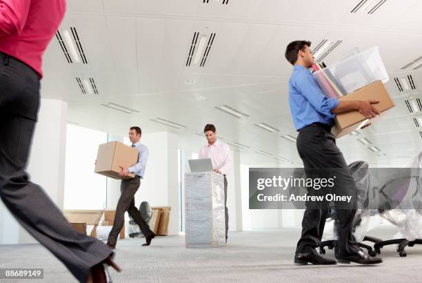 businessmen moving boxes into new office - cambio de oficina fotografías e imágenes de stock