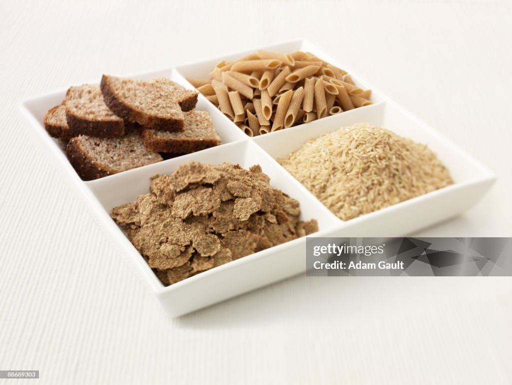 Close up of sectioned plate with bread, pasta, rice and cereal