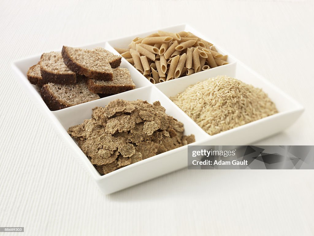 Close up of sectioned plate with bread, pasta, rice and cereal