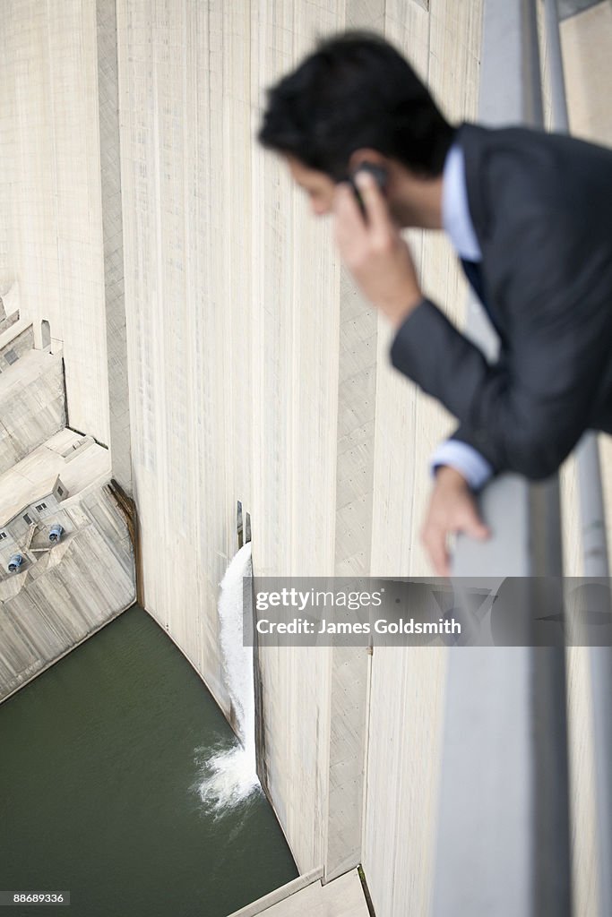 Businessman looking at water spilling from dam