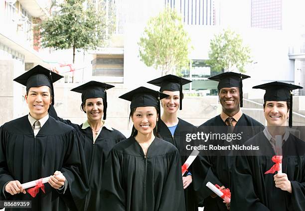 graduates in caps and gowns with diplomas - degree stock pictures, royalty-free photos & images