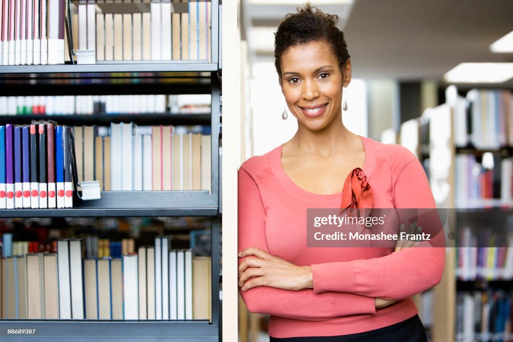 Librarian leaning on shelves in library