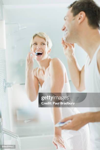 couple brushing teeth in bathroom - couple brushing stock pictures, royalty-free photos & images