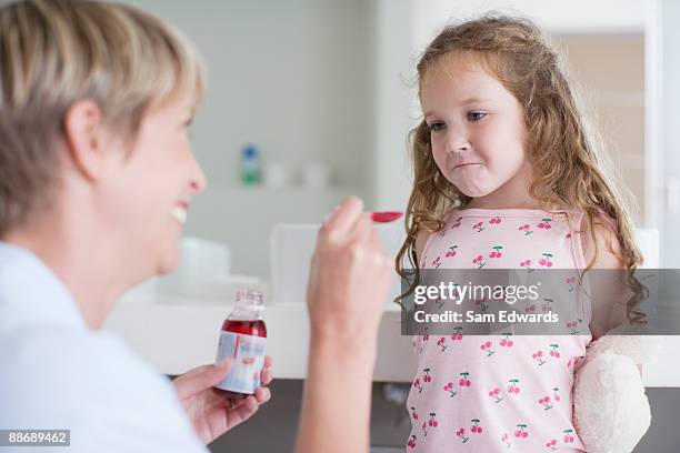 mãe dando medicamento a persistente médico - teimoso - fotografias e filmes do acervo