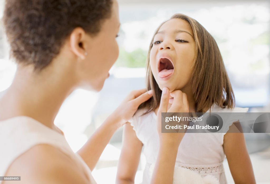 Woman checking sick daughters throat