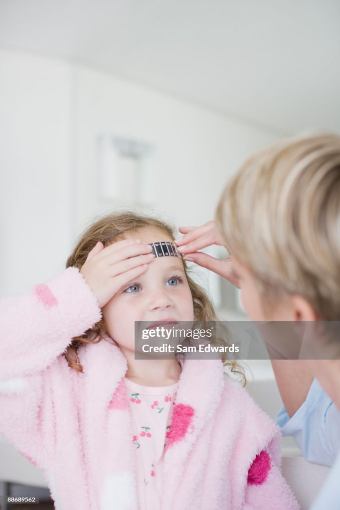 Mother taking daughters temperature