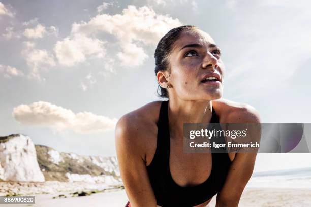 exhausted young female runner taking a break on beach - sudor fotografías e imágenes de stock