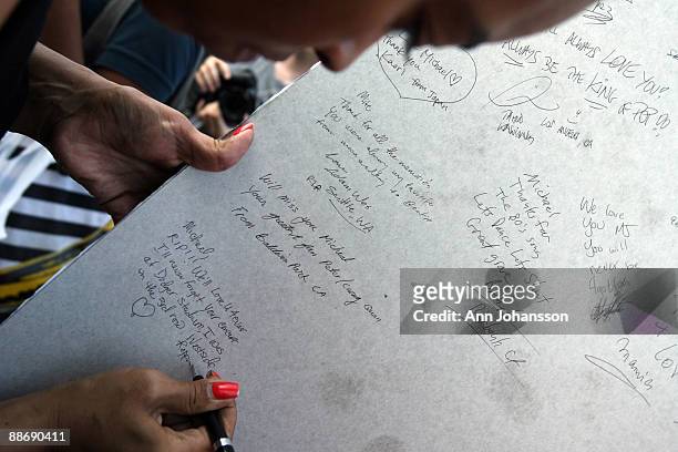 Leah Moore signs the back of a Michael Jackson poster as people gather to mourn Jackson's death at UCLA Medical Plaza June 25, 2009 in Los Angeles,...