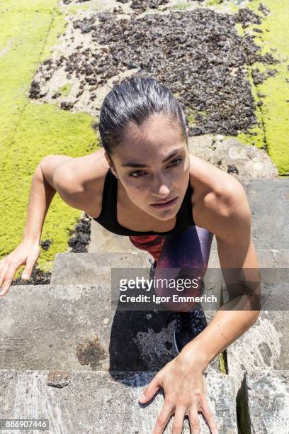 young female free runner climbing up sea wall - igor emmerich stock pictures, royalty-free photos & images