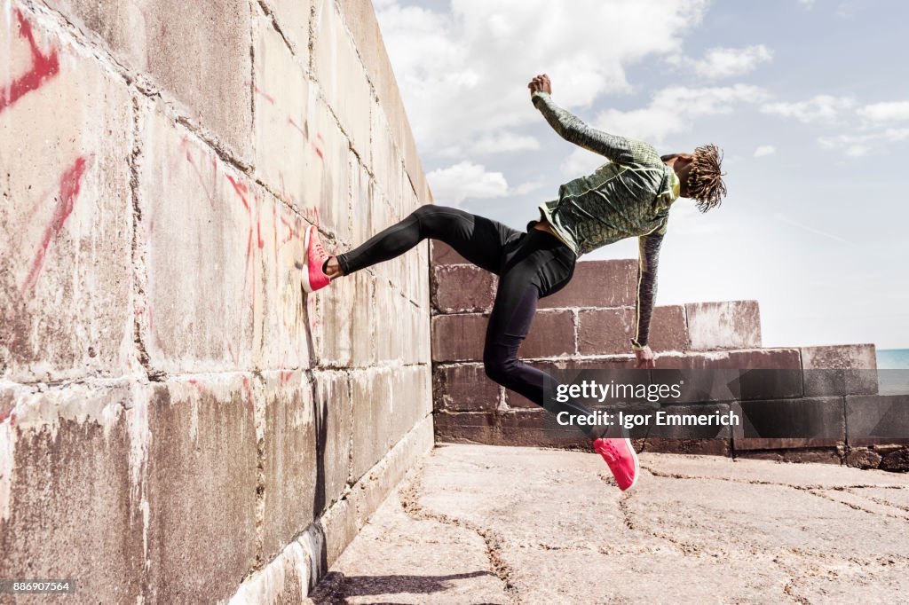 Young man, free running, outdoors, running up side of wall