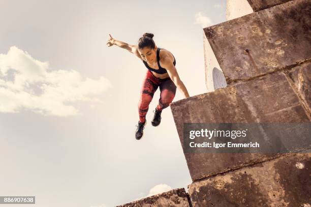 young female free runner jumping down sea wall - le parkour fotografías e imágenes de stock