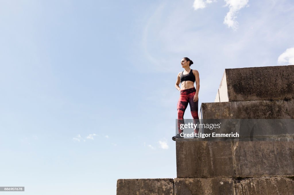 Young female free runner looking out from top of sea wall