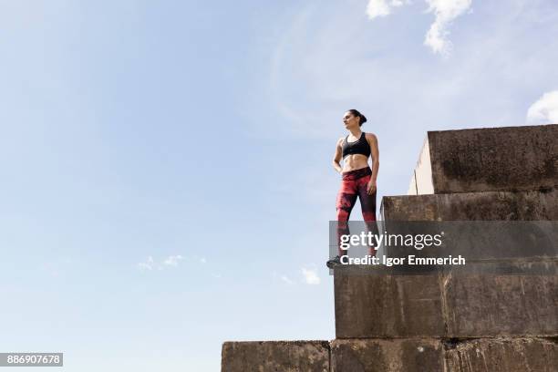 young female free runner looking out from top of sea wall - igor emmerich stock pictures, royalty-free photos & images