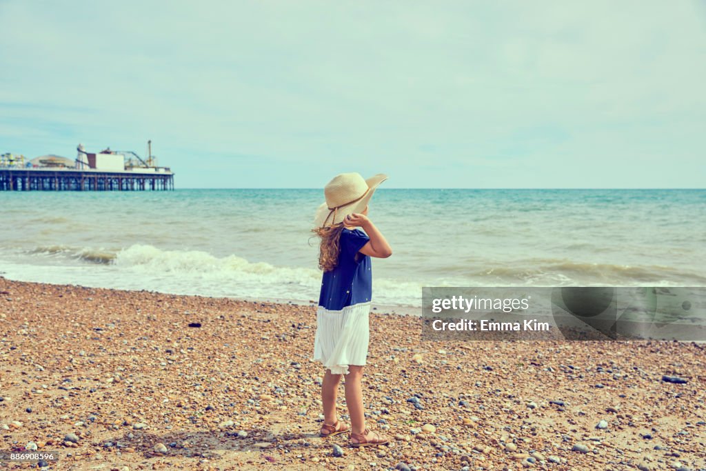 Young girl, standing on beach, looking at view