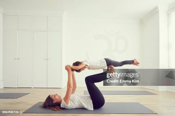 mother and daughter in yoga studio, daughter balancing on mothers legs - trust exercise stock pictures, royalty-free photos & images